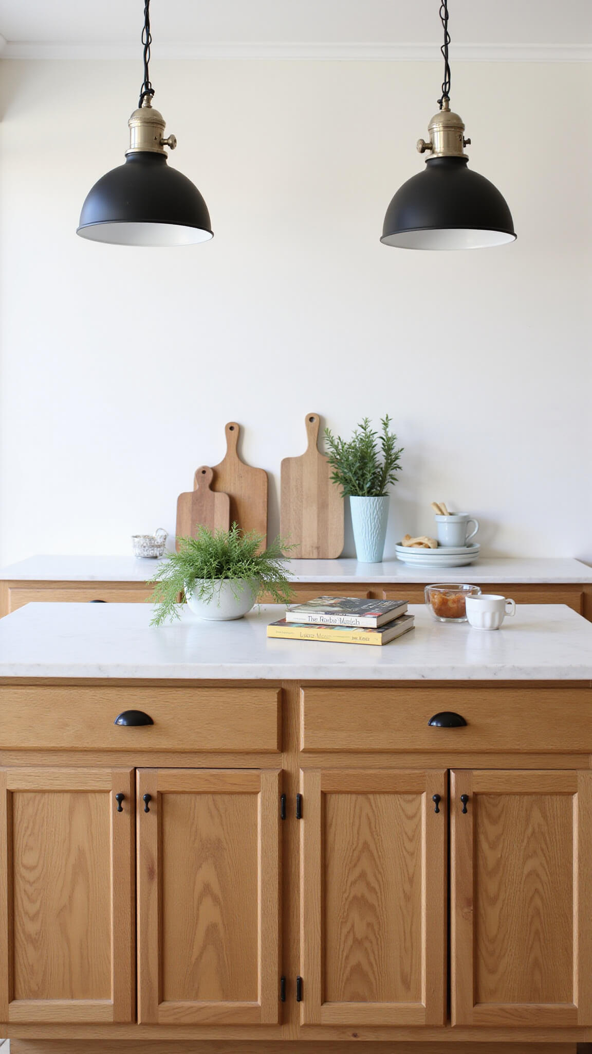 Golden oak kitchen island with white quartz top, styled with cutting boards, herbs, and cookbooks, under industrial pendant lights.