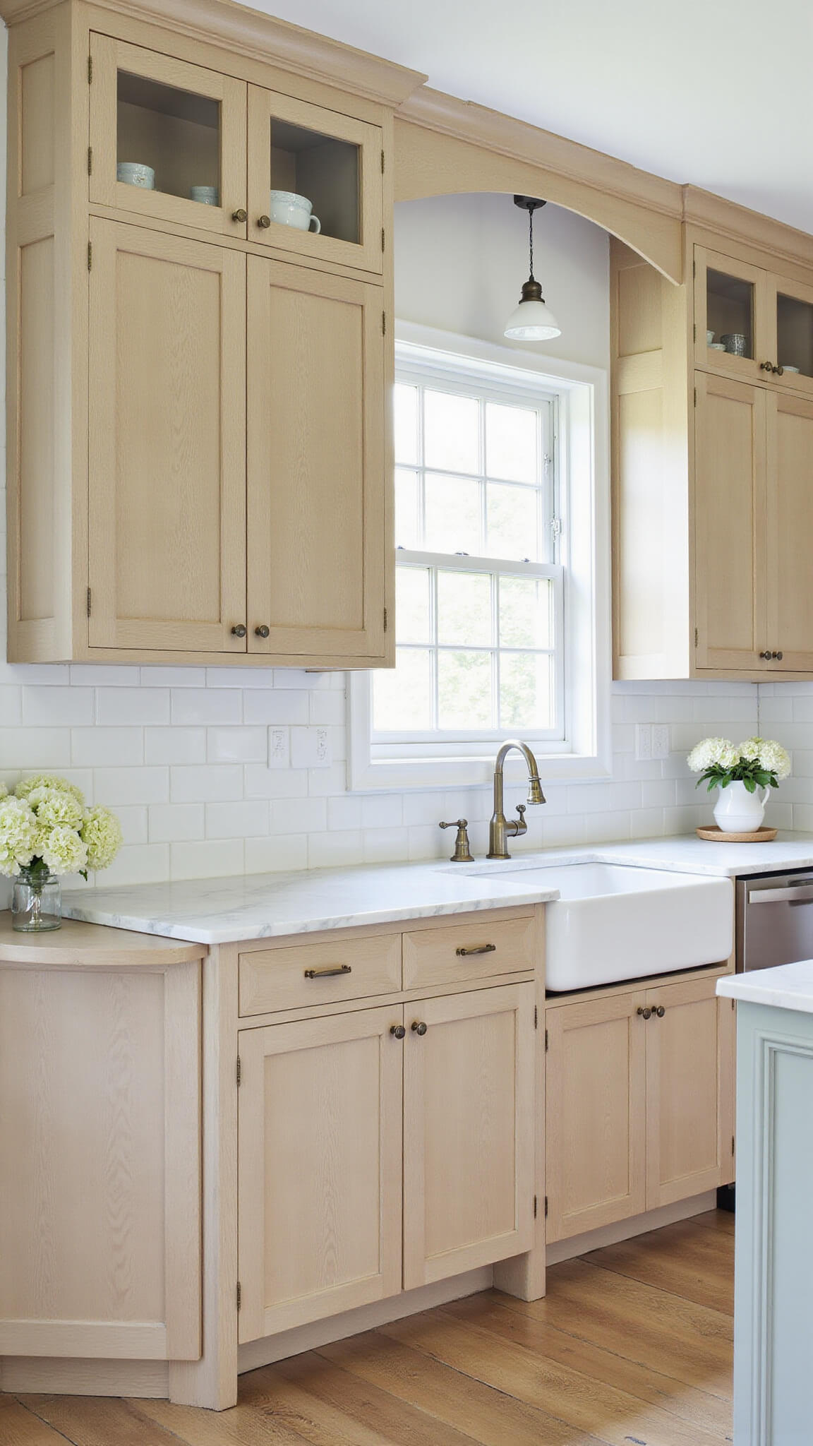 Transitional 13x16ft kitchen with pale oak cabinets, white subway tile, honed marble counters, glass-front uppers, and vintage decor in natural morning light.