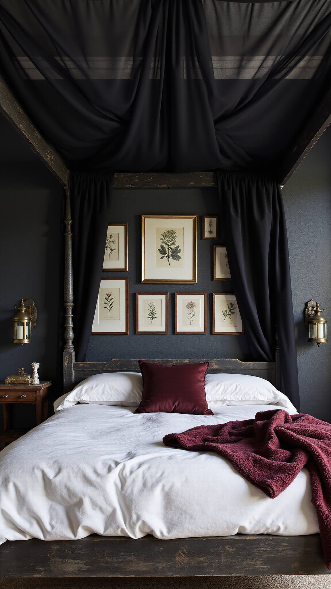 Dramatic canopy bed with sheer black drapes, white linen bedding, and burgundy throws in moody, vintage bedroom with botanical prints and antique brass lanterns.