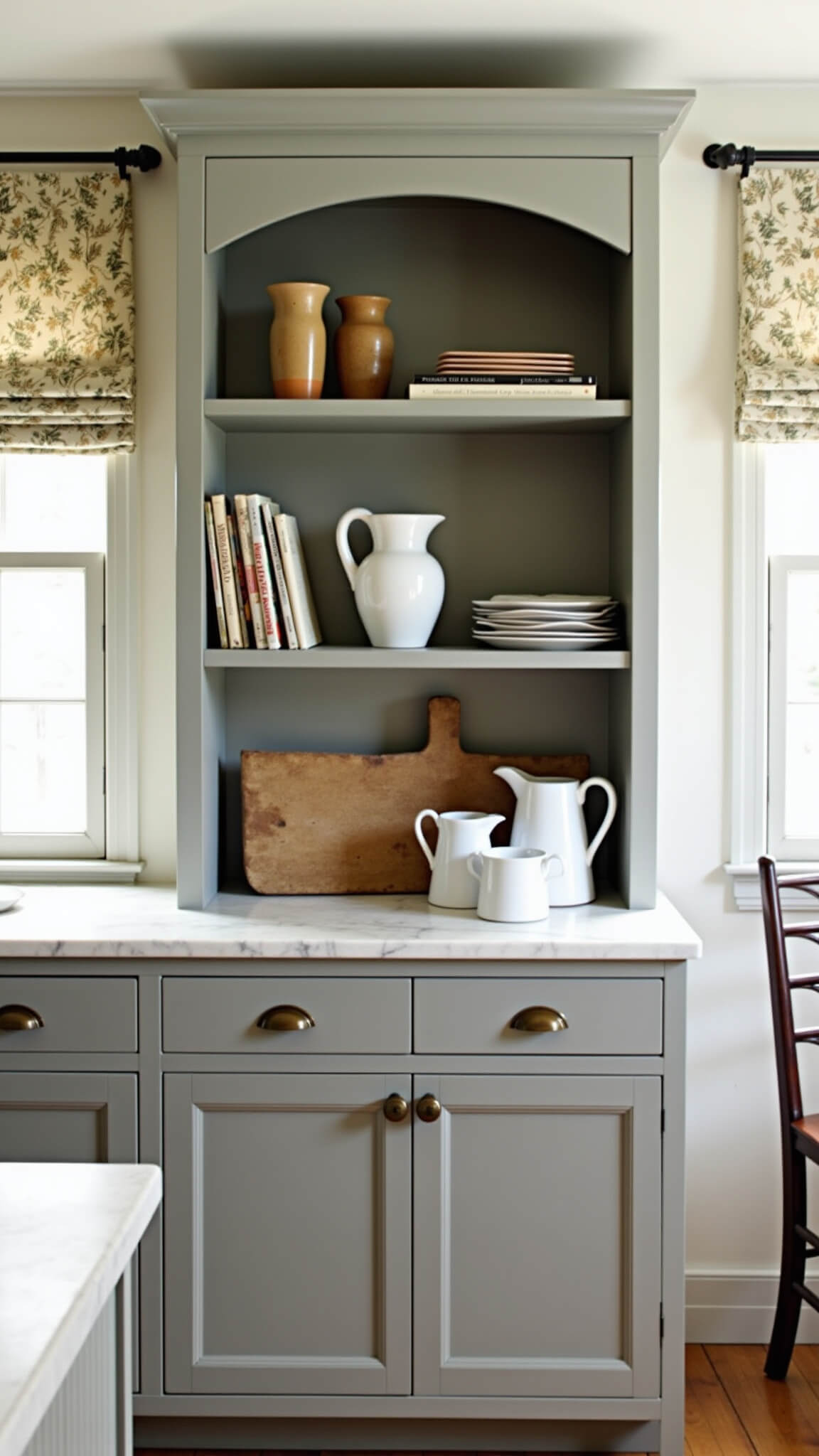 Shaker-style dove grey hutch in cozy kitchen nook with pottery, vintage books, and enamelware, bathed in soft morning light.