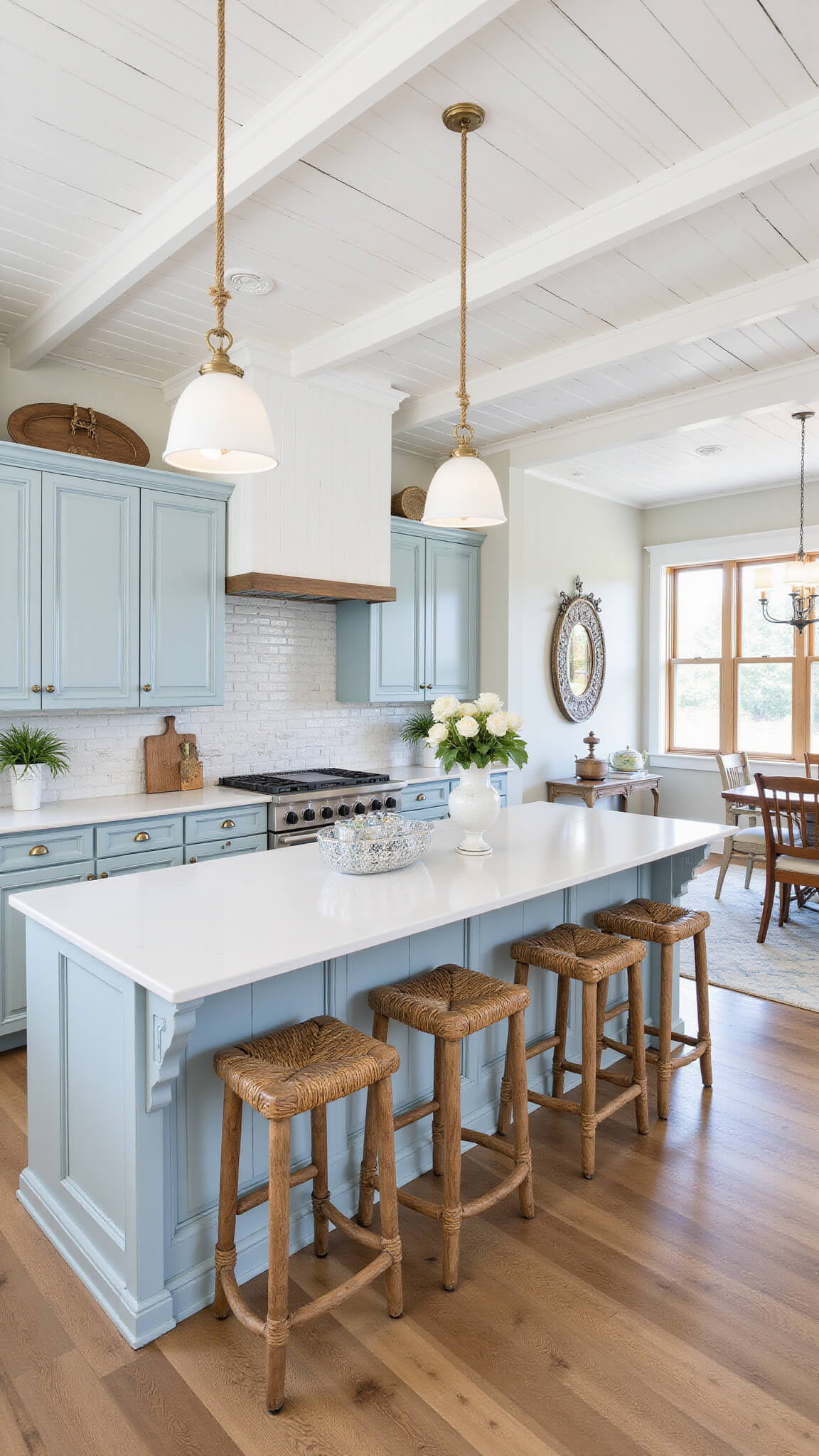 Coastal-style kitchen with light blue distressed cabinets, white subway tiles, rope pendant lights, rattan barstools, and nautical decor in bright natural light.